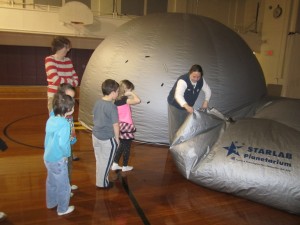 Amanda Williams helps grade 1 students into planetarium. Photo by Wende Carr