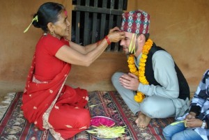 Paul Josephson as his friend's mom gives him a tika, a red mark on his forehead, for Dashain, a hundu Nepali festival