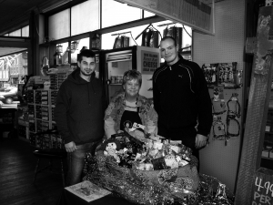 Bonnie Baker, center, with Mario Elenkov and Areksandar Dachev, Old Forge Hardware's newest employees from Sofia, Bulgaria, show off the Hardware's raffle basket to benefit the Strand Theatre. Photo by Dana Armington