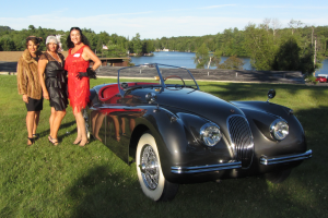 Stephanie Clark and her entourage next to Cary Grant's Jaguar convertible, displayed at the event