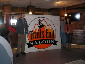 Brian, Chris and Lisa Murphy, from left, with the sign for their new Trails End Saloon. Photo by Marianne Christy