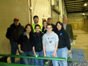 Key Club and Kiwanis Members sand and paint slats for Main St. Benches. Front Row: Left to Right. - Sam Notley, Ryan Johnston, David Ehrensbeck, Diane Amos. Middle Row: Left to Right - Dick Olson, Will Johnson, Shelby Egnaczyk. Back Row: Left to Right - Tom Smedley and Chris Kraft. Courtesy photo