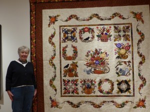 Claire Oehler, chairman of the 28th Annual Quilts Unlimited Exhibition, with the Best of Show winning quilt, Baltimore Autumn, by Melanie Rodriguez of Fredericksburg, VA. The quilt also took first place in the Bed Quilt category. Photo by Michele deCamp
