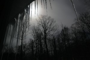 A full moon backlights  a row of icicles