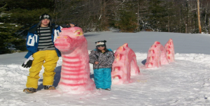 Tayler and Ella Schmid with their snow-sculpted sea monster. 